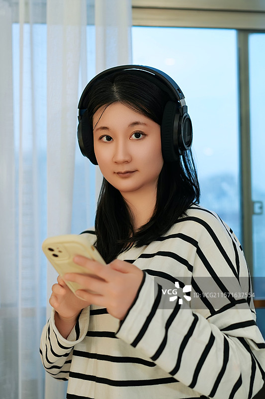 戴耳机玩手机的女孩图片素材