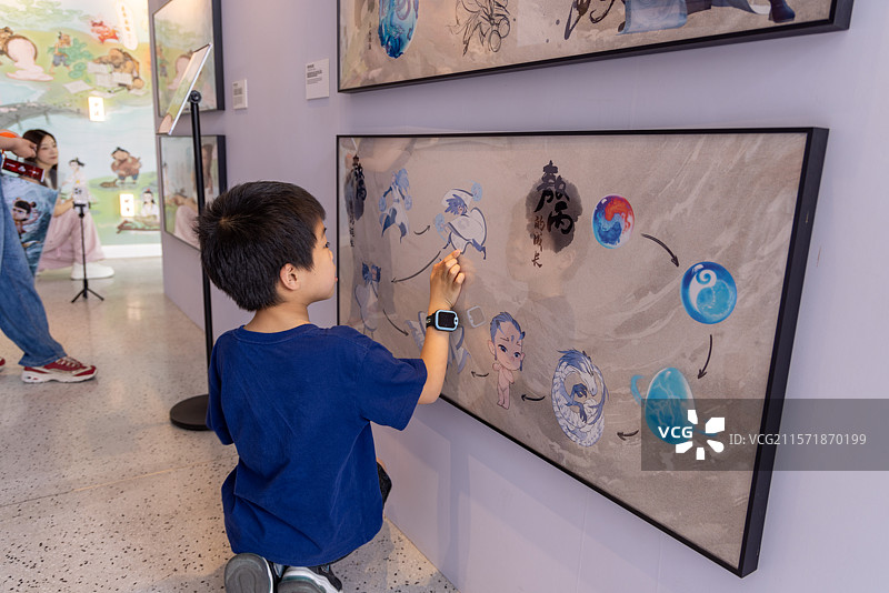 小男孩在动画电影哪吒幕后创作展里观看原画图片素材