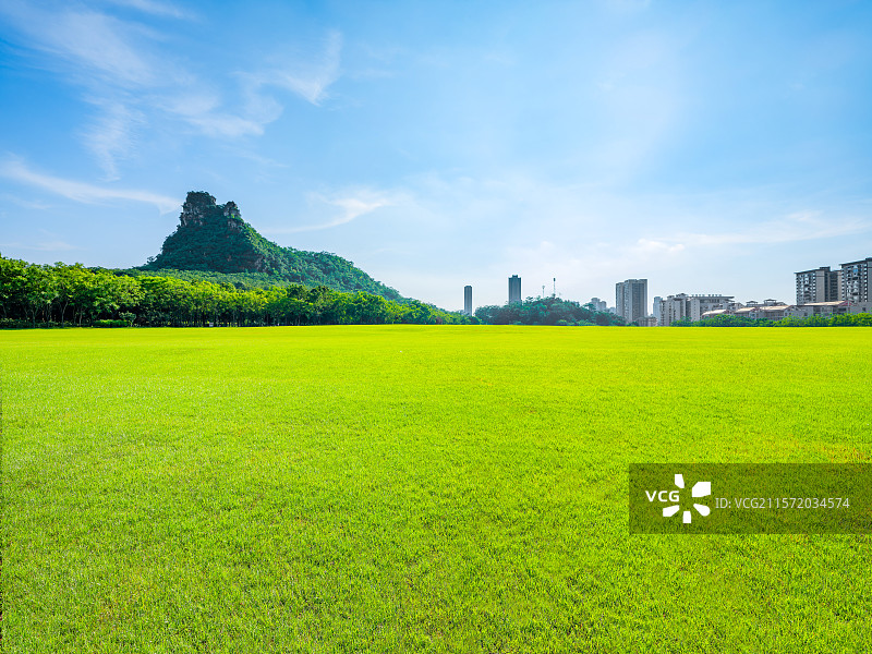 广西柳州马鹿山公园整齐的大草坪、草地与青山绿树城市建筑蓝图白云风光图片素材