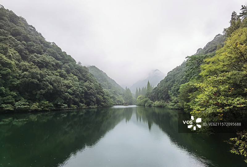 宁海森林温泉公园景区风景，两岸的山往一个方向延伸，水面倒映山色，天空雾气蒙蒙图片素材