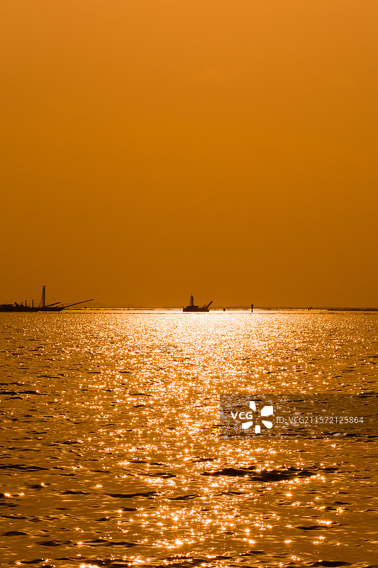 金色海面的静谧渔船剪影图片素材