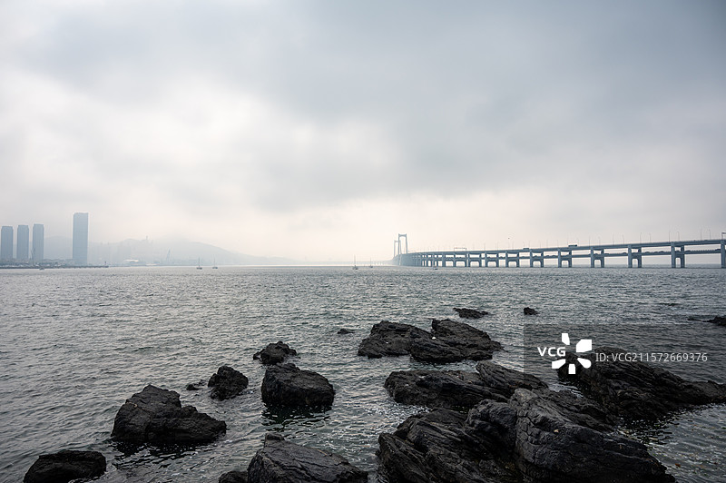 云雾中的天空衬托着海滨城市的景色，云雾中的大连星海湾跨海大桥图片素材