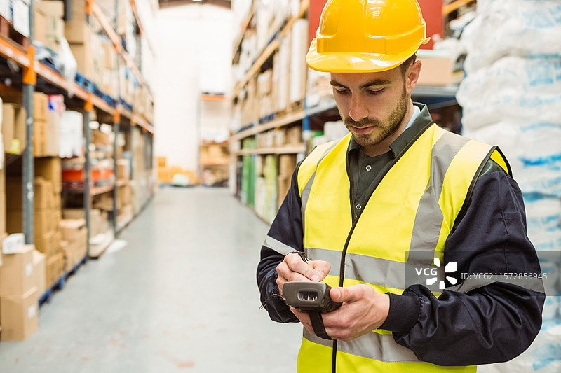 穿着高可视性背心的男子在仓库中使用手写笔扫描货架，留有空白空间图片素材