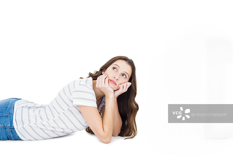 穿着条纹上衣和牛仔裤的女人趴在白色背景上，托着下巴向上看。图片素材