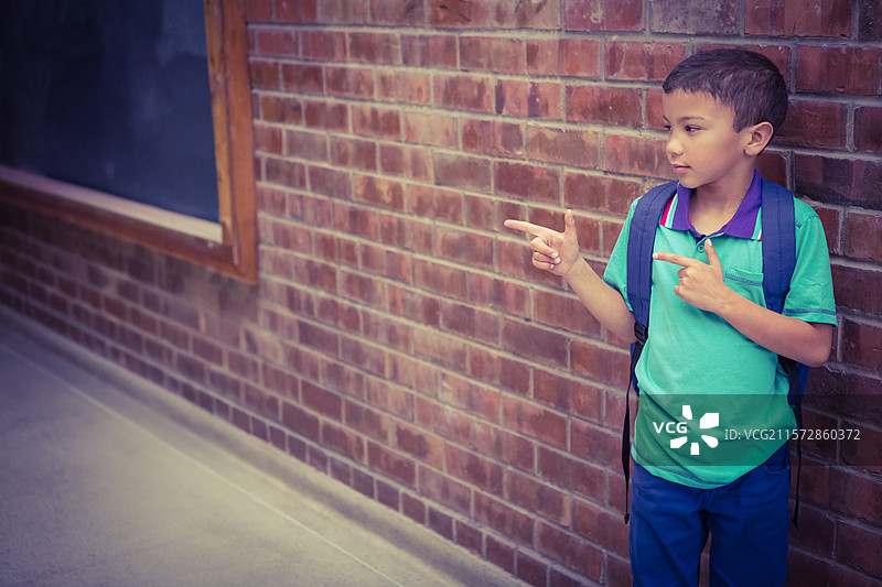 亚洲男孩靠在学校走廊的黑板旁，背着书包，留有空白空间图片素材