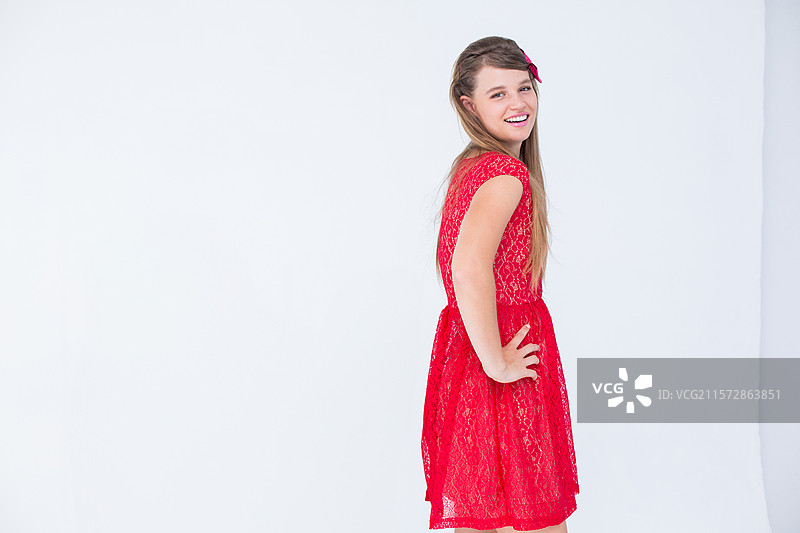 穿着红色蕾丝裙、头戴红色发带的女性在白色摄影棚背景前摆姿势，留有空白空间。图片素材
