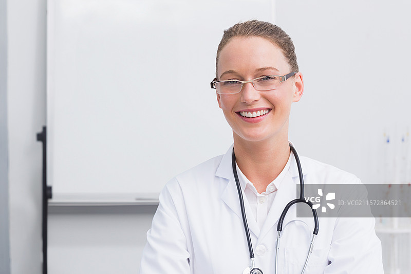 穿着白大褂的女医生站在诊所里，旁边有试管和黑板，配有听诊器，留有空白空间。图片素材