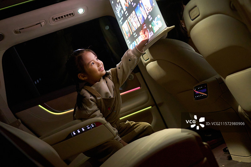 一位东方小女孩在汽车里触摸电子显示屏图片素材