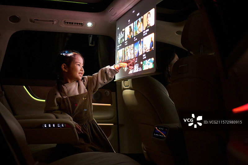 一位东方小女孩在汽车里触摸电子显示屏图片素材