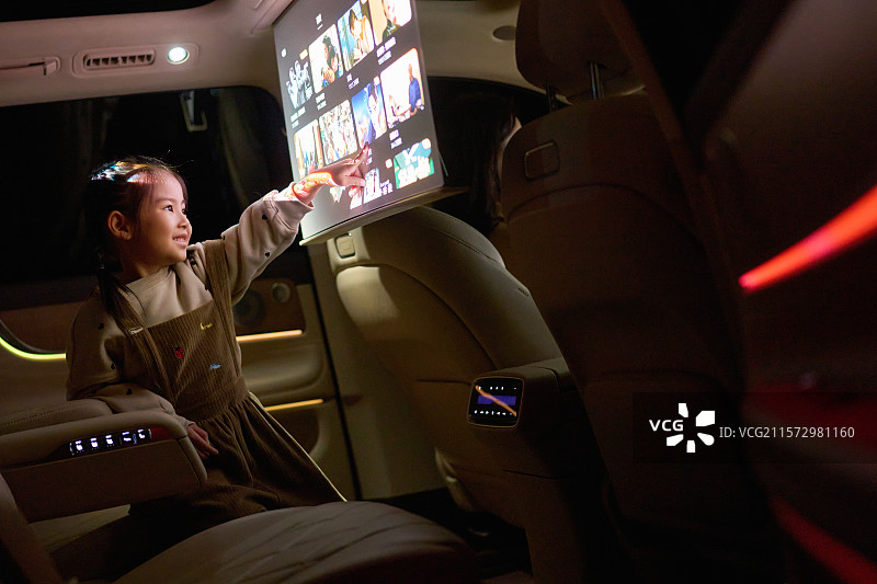 一位东方小女孩在汽车里触摸电子显示屏图片素材