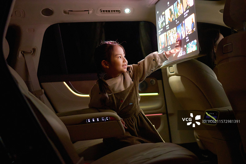 一位东方小女孩在汽车里触摸电子显示屏图片素材