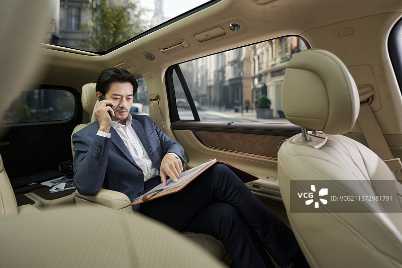 商务男人坐在汽车后座打电话图片素材