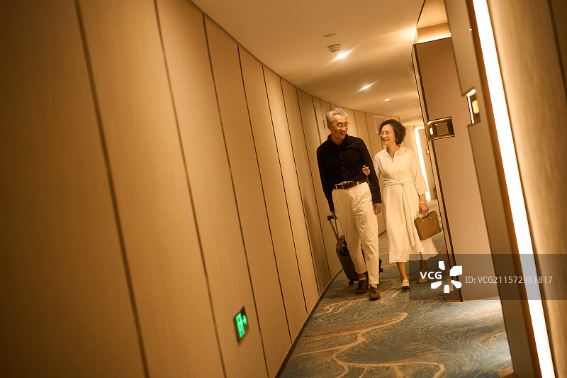 老年夫妇臂挽臂拉着皮箱走向酒店客房图片素材