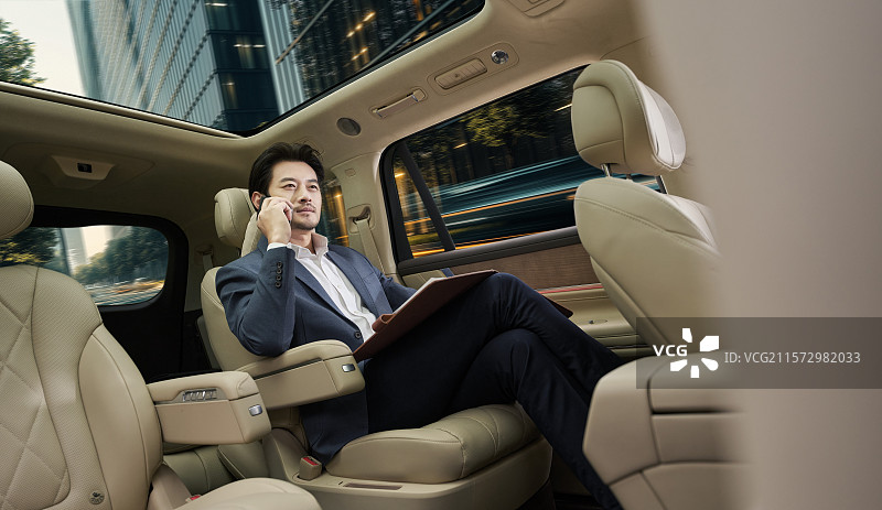商务男人坐在汽车后座打电话图片素材