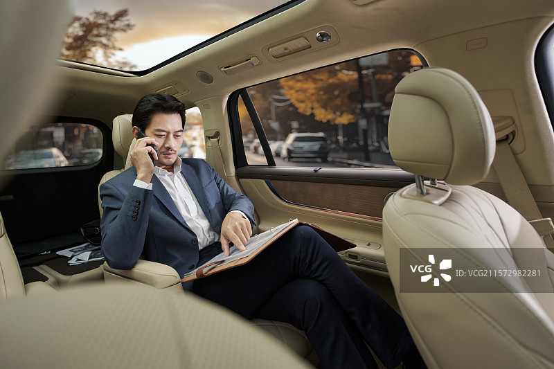 商务男人坐在汽车后座打电话图片素材