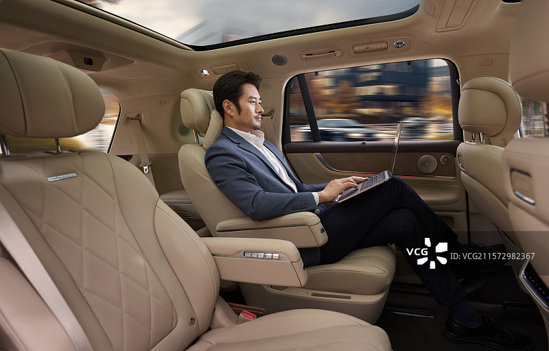 商务男人坐在汽车后座使用电脑图片素材