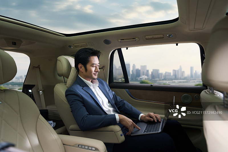 商务男人坐在汽车后座使用电脑图片素材
