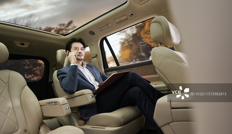 商务男人坐在汽车后座打电话图片素材