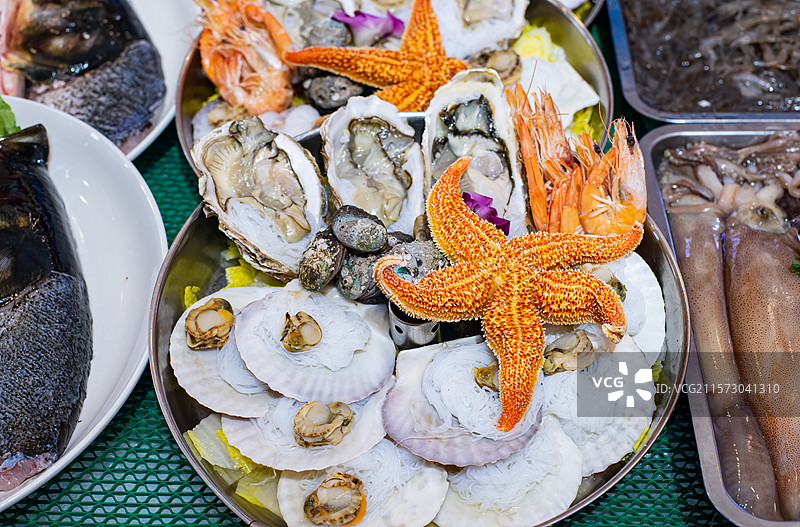 中国蔬菜篮子拍摄主题，盘子里装满了新鲜的海鲜扇贝蛤蜊海星生蚝鱿鱼，室内无人图像摄影图片素材