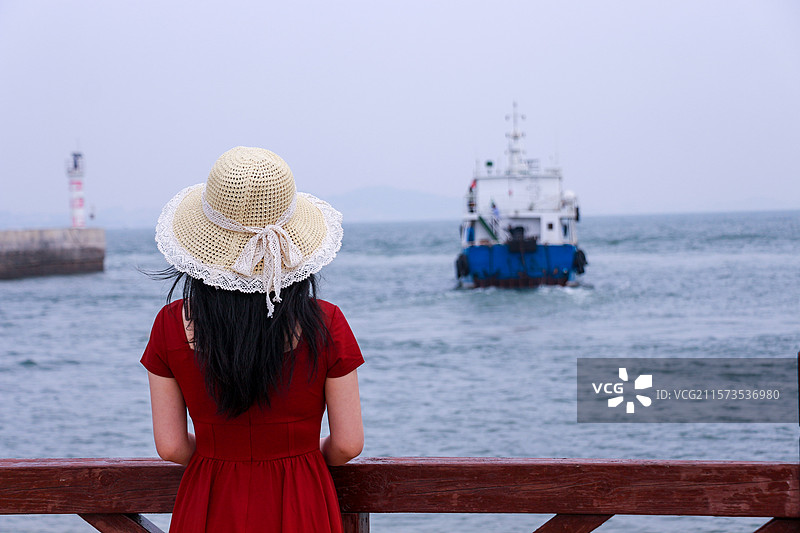 葫芦岛市觉华岛海岸上扶着围栏的少女背影图片素材