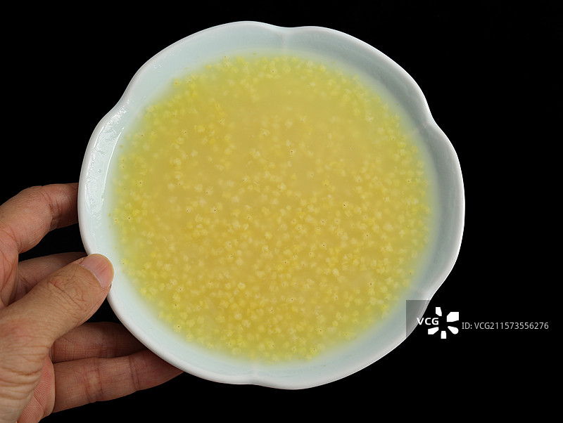 黑色背景上农民双手捧着一碗秋天立秋丰收的美食小米粥图片素材