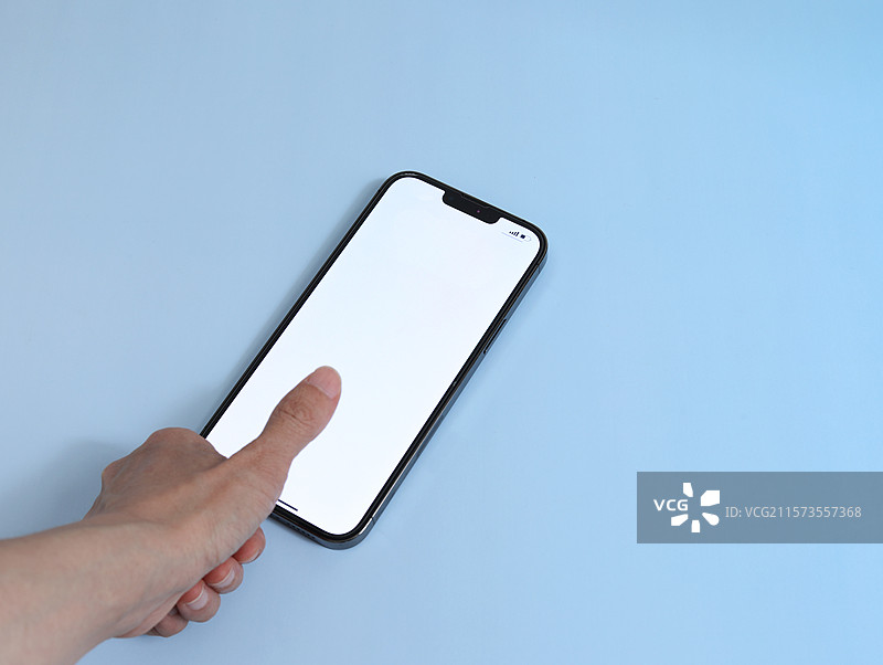 蓝色桌面上摆放着一部屏幕空白的智能手机图片素材