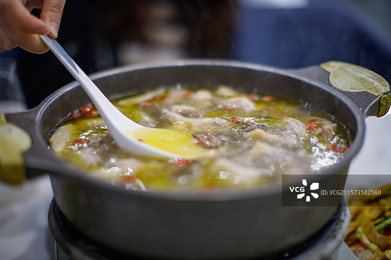 汤匙从精致的石锅中盛鸡汤图片素材