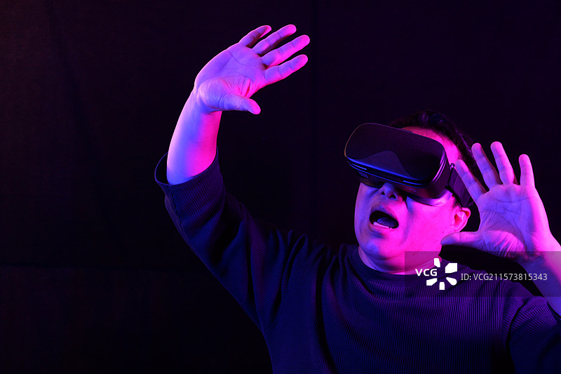 一个亚洲男人佩戴VR眼镜，正在沉浸体验VR虚拟现实世界图片素材