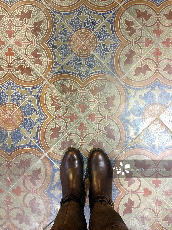 正上方俯拍棕色皮靴站在斑驳的老北京花砖上图片素材