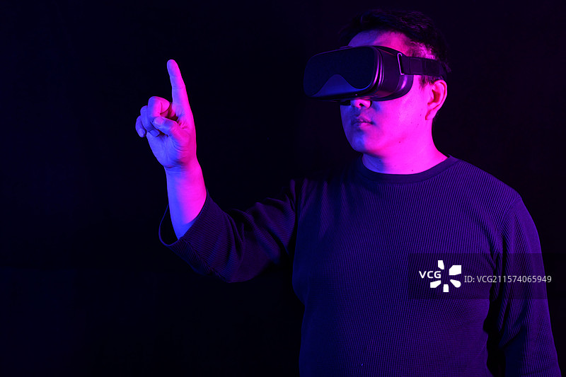 一个亚洲男人佩戴VR眼镜，正在沉浸体验VR虚拟现实世界图片素材