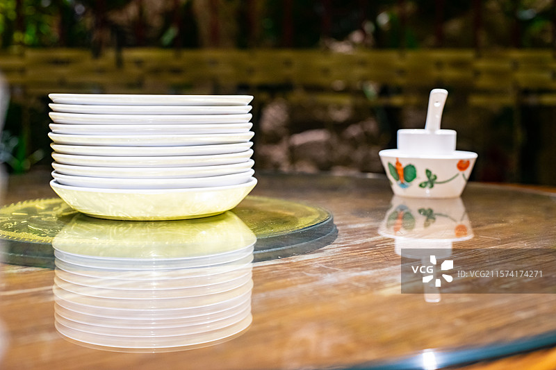 中国餐饮餐厅饭店饭馆行业，空的餐桌拍摄主题，中国传统木制圆桌上的叠起来的餐具，室内无人图像摄影图片素材