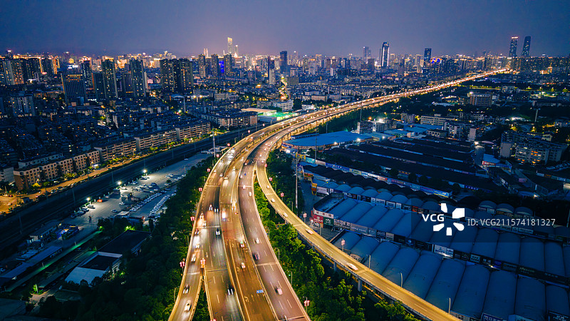 航拍昆明明波立交桥充满活力的夜景，展示照明的道路和城市灯光图片素材
