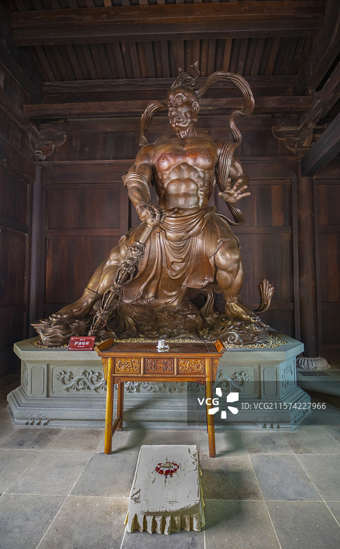 唐代传统木质寺庙建筑风格屋顶下木板墙壁前左手推掌右手提荡魔杵弓步站立刚毅威猛安福寺护法哈将纯木雕像图片素材