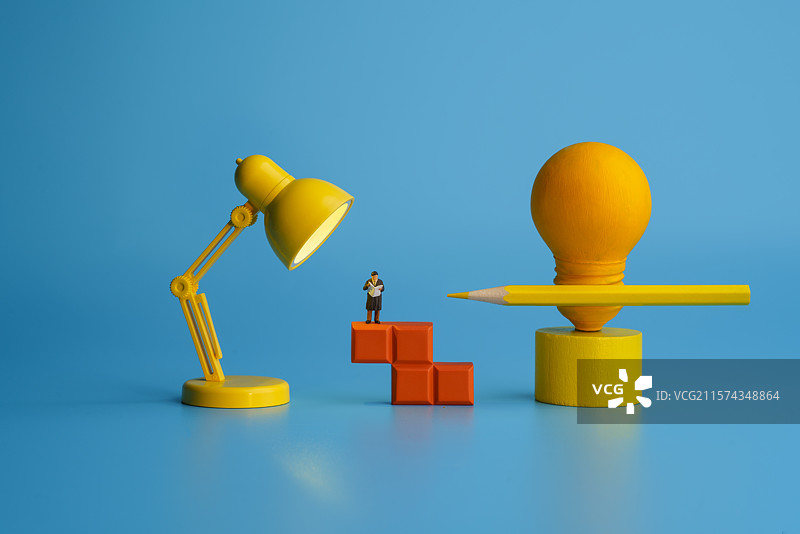 蓝色背景下的阅读者和铅笔灯泡微缩创意图图片素材