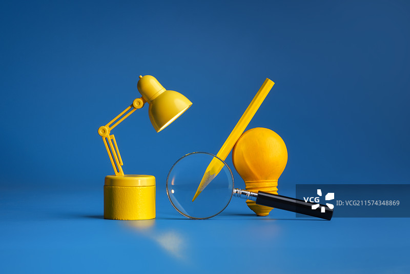 蓝色背景下灵感灯泡台灯铅笔和放大镜微缩创意图片素材