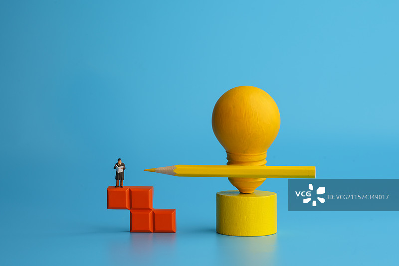 蓝色背景中站在积木上看书的男士和灯泡铅笔微缩创意图图片素材
