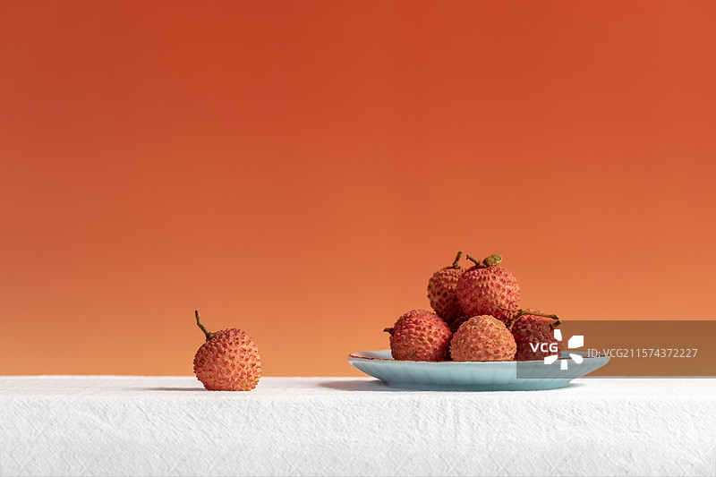 红色背景下放在桌子上的荔枝图片素材