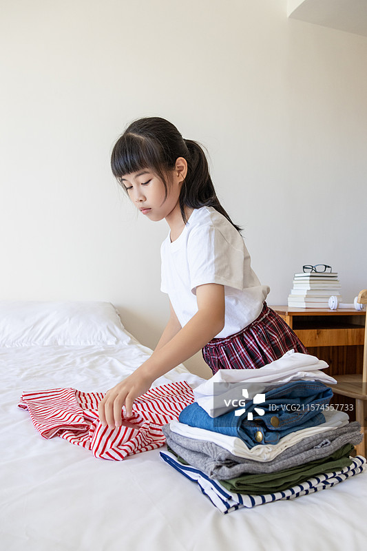 中国小女孩在卧室里叠衣服图片素材