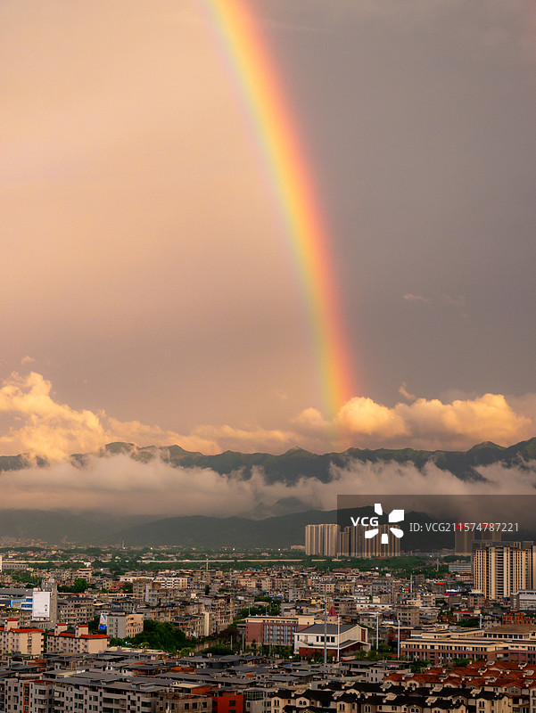 傍晚雨后城镇上空的绚丽彩虹，群山云雾缭绕图片素材