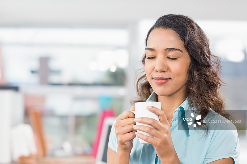 白色陶瓷杯在桌子上冒着热气，旁边是模糊的书架和书籍，装饰在自然光下。图片素材