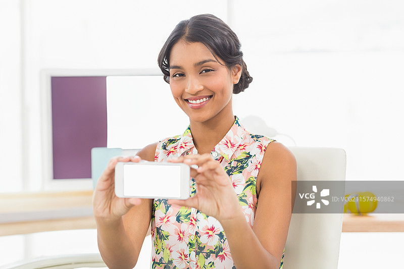 智能手机放在整洁的办公室桌子上，旁边有双显示器和一个黄色的减压球，窗户旁边。图片素材