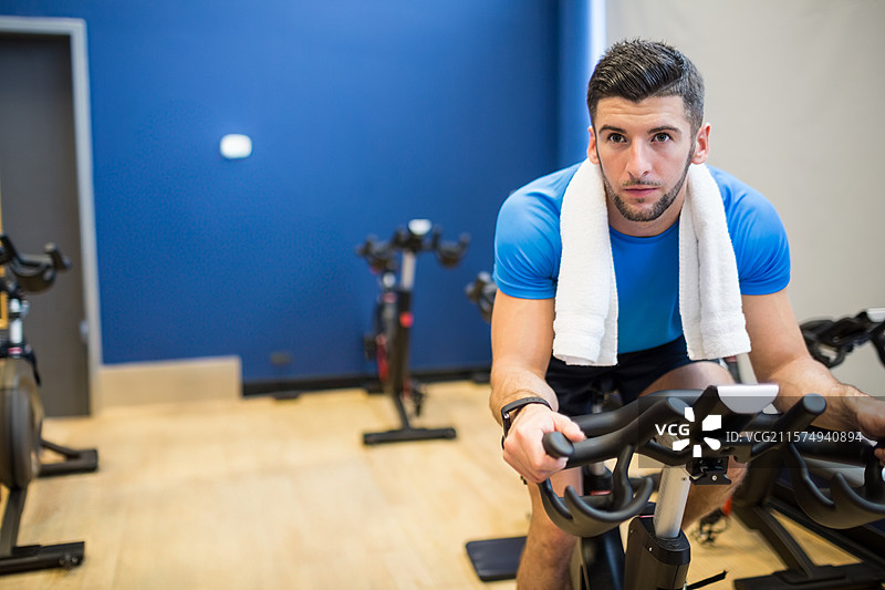 健身单车排成一排，靠在明亮的蓝色墙壁上， resting on light wood floor near doorway图片素材