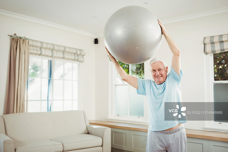 银色健身球漂浮在阳光明媚的客厅中，靠近条纹窗帘的软垫沙发上。图片素材