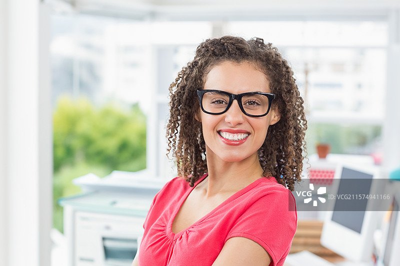 黑色厚边眼镜放在明亮办公室的桌子上，旁边是打印机和显示器，留有空白空间图片素材