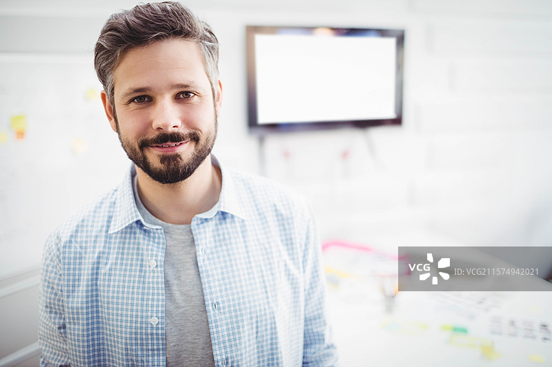 男子站在明亮的办公室规划空间，研究白板上的便利贴，靠近桌子。图片素材