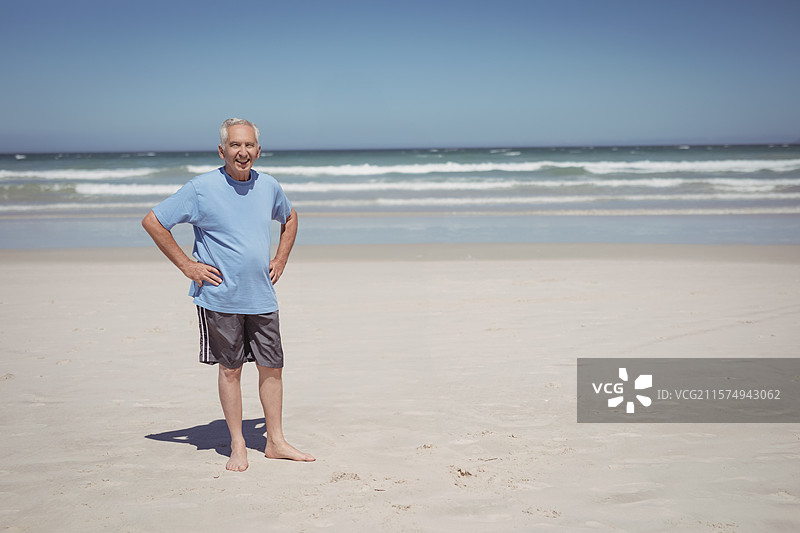 赤脚站在沙滩上的老年人，身后是温柔的海浪与地平线，留有空白空间。图片素材