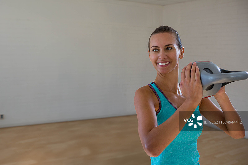 女性在健身工作室的木地板上举起胸前的壶铃，留有空白空间图片素材