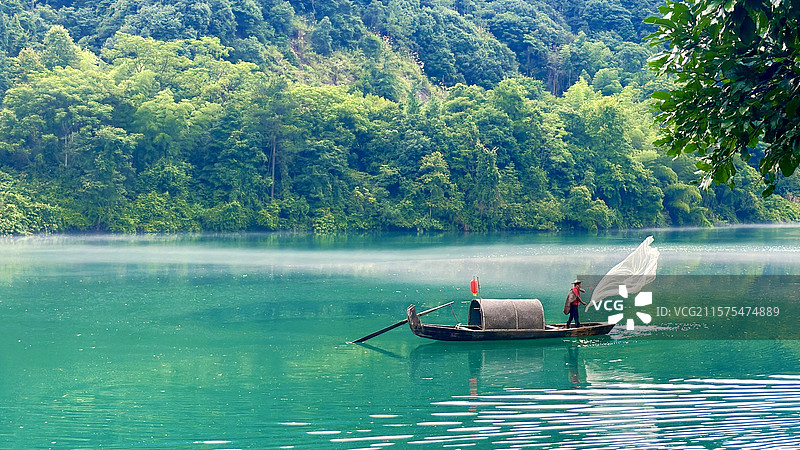 湖面小船上撒网的人图片素材