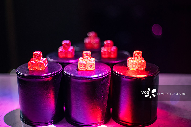 中国休闲娱乐拍摄主题，KTV桌子上上成一排黑色的皮革杯子和一堆红色的骰子，室内无人图像摄影图片素材