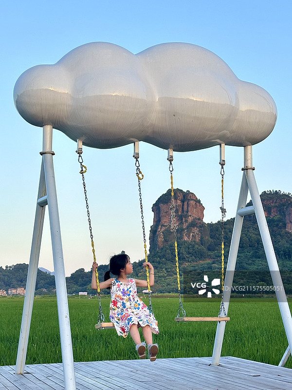 夏日傍晚，小女孩在浙江临海桃江十三渚｜桃渚油菜花田｜石柱峰前荡秋千乘凉消暑图片素材
